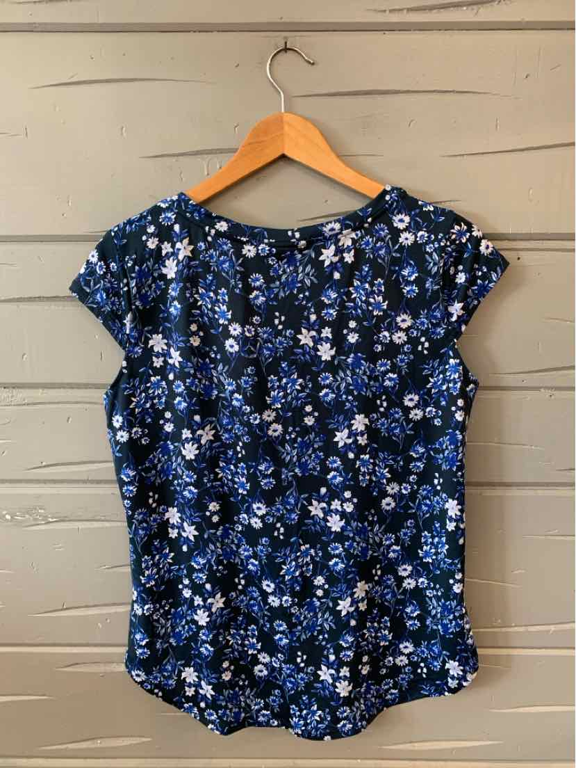 Navy blue floral blouse with short sleeves and round neckline on wooden hanger.
