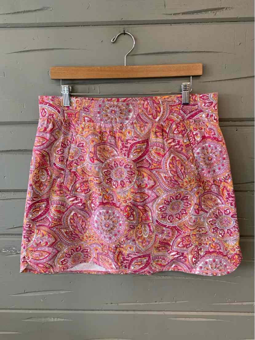 Pink paisley patterned skirt with a scalloped hem hanging on a wooden hanger.