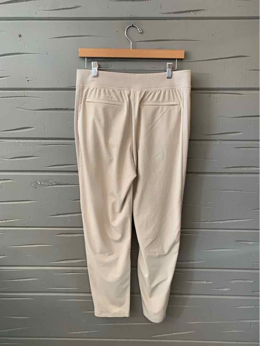 Beige women's athletic pants with elastic waistband and tapered legs, size 8.