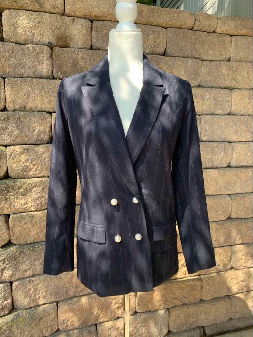 Navy blue double-breasted blazer with gold buttons and notch lapels on a white mannequin.