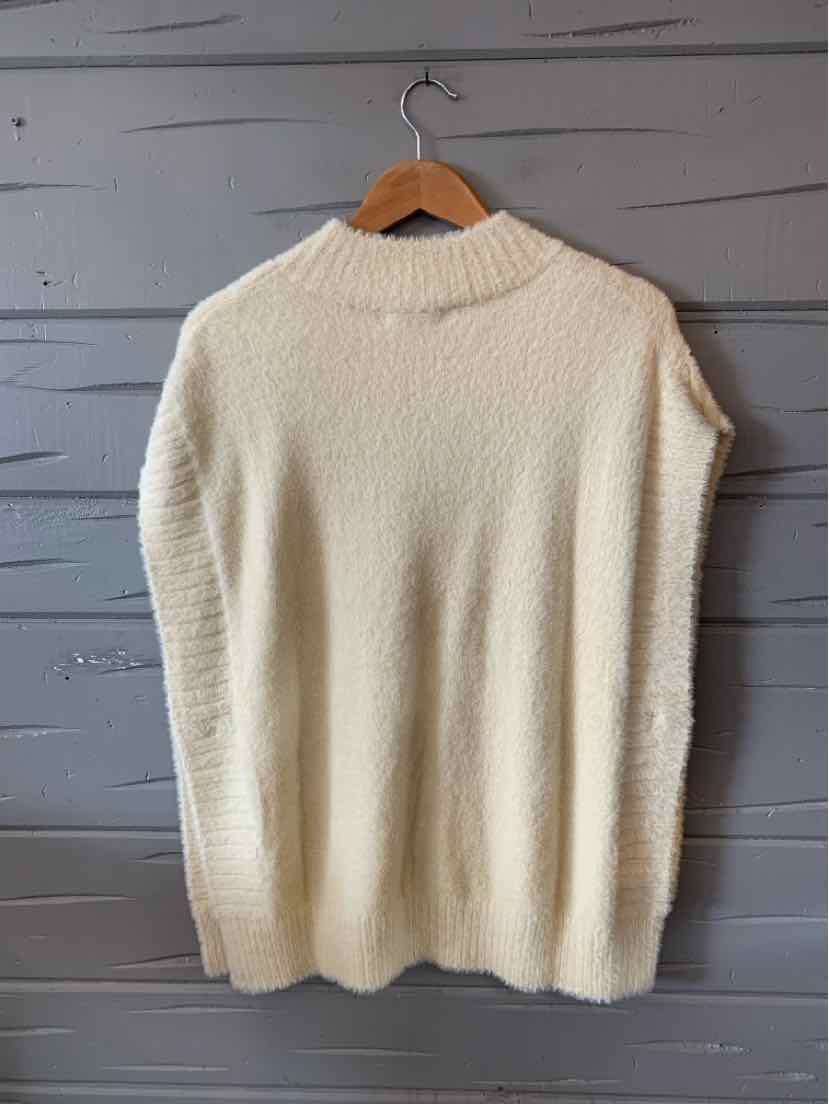 Cream-colored knit sweater vest with ribbed collar and sleeveless design hanging on wooden hanger.