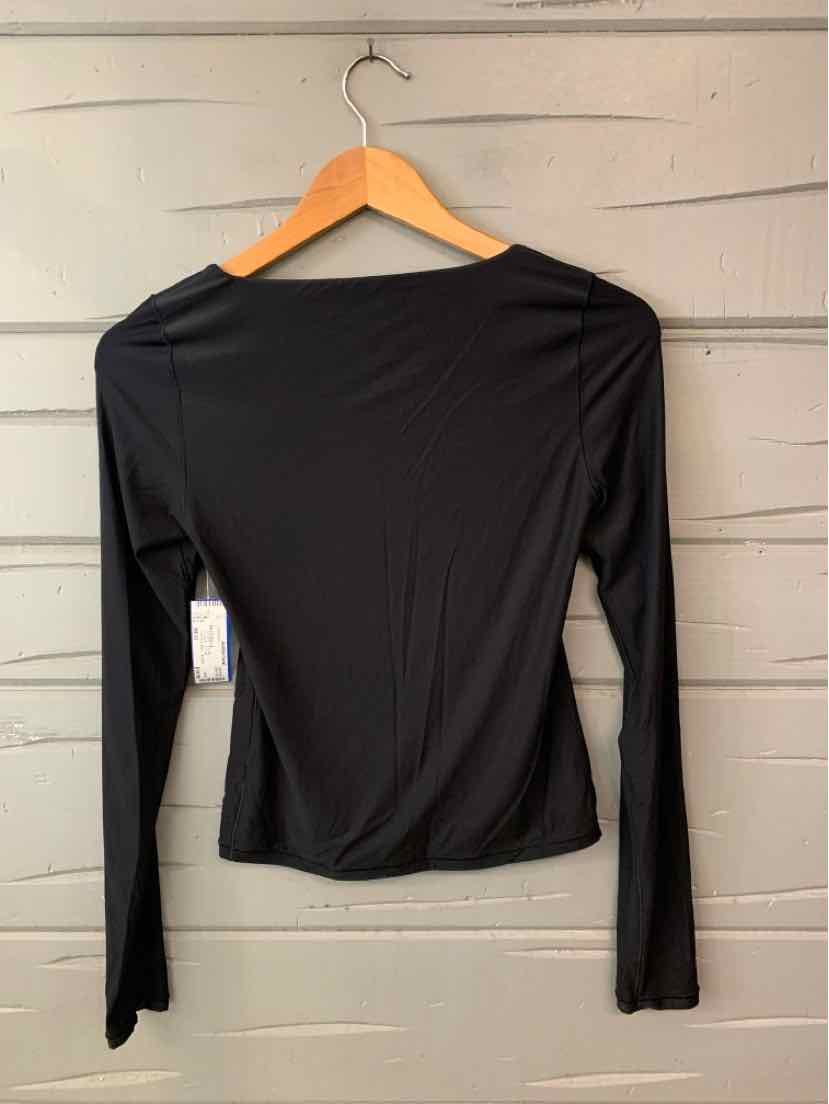 Black women’s long-sleeve top with a simple solid design and relaxed fit, hanging on a wooden hanger.