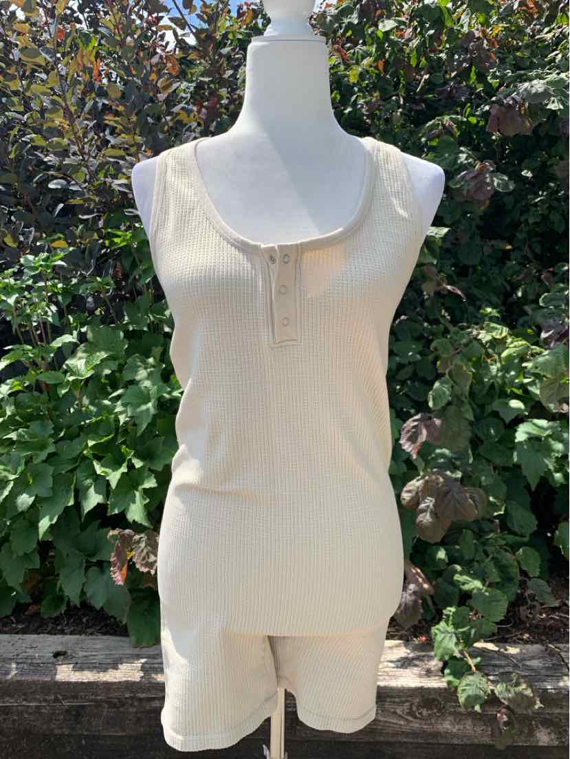 Tan sleeveless tank top and matching shorts set in lightweight fabric displayed on a mannequin outdoors.