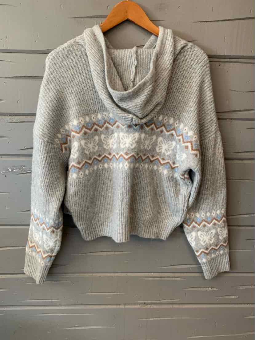 Light gray knit hoodie with patterned zigzag stripes in white and beige across chest and sleeves.