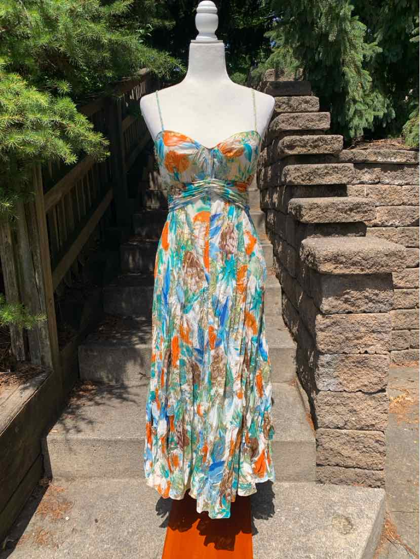 Multicolor sleeveless midi dress with fitted bodice and flowing skirt on dress form outdoors.
