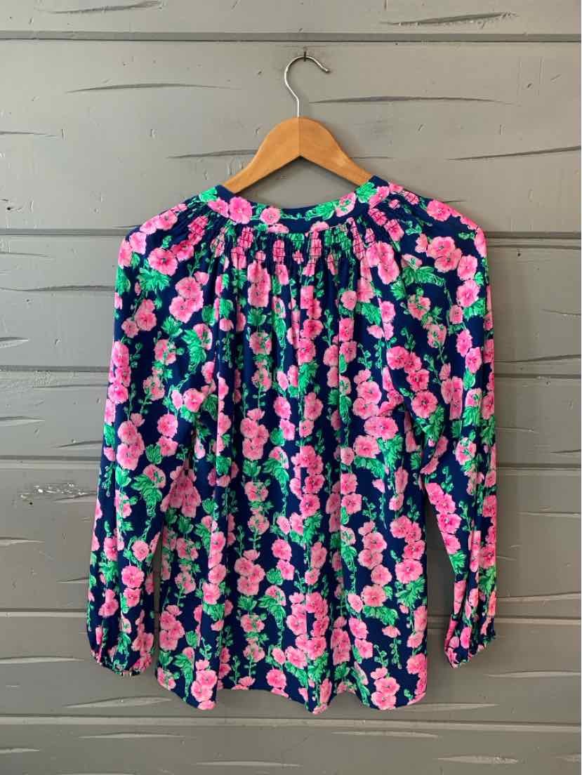 Long-sleeve blouse with navy background and bright pink floral print, gathered neckline, and loose fit.