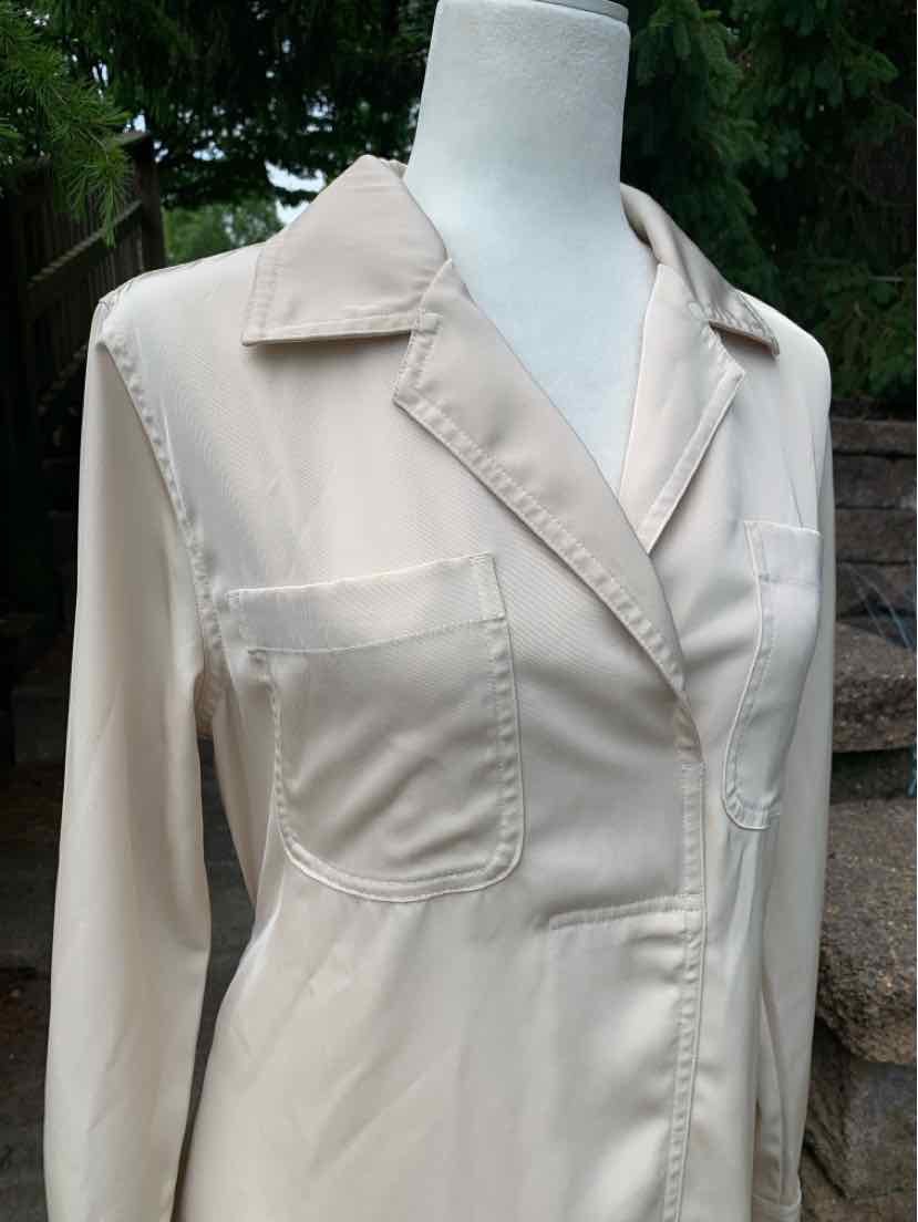 Light beige long-sleeve shirt with a pointed collar and two front chest pockets on a mannequin.