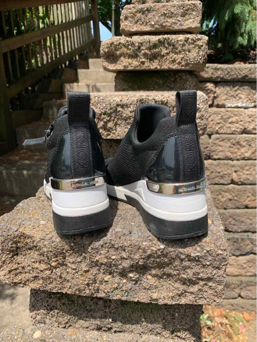 Black Michael Kors sneakers with white platform soles and metallic silver heel accents, size 6.