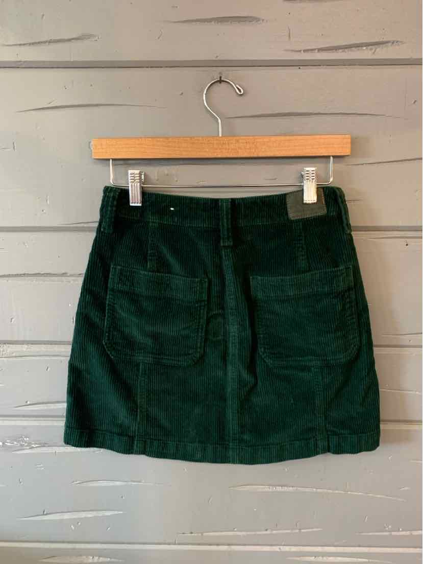 Dark green corduroy mini skirt with front patch pockets and a subtle A-line shape.
