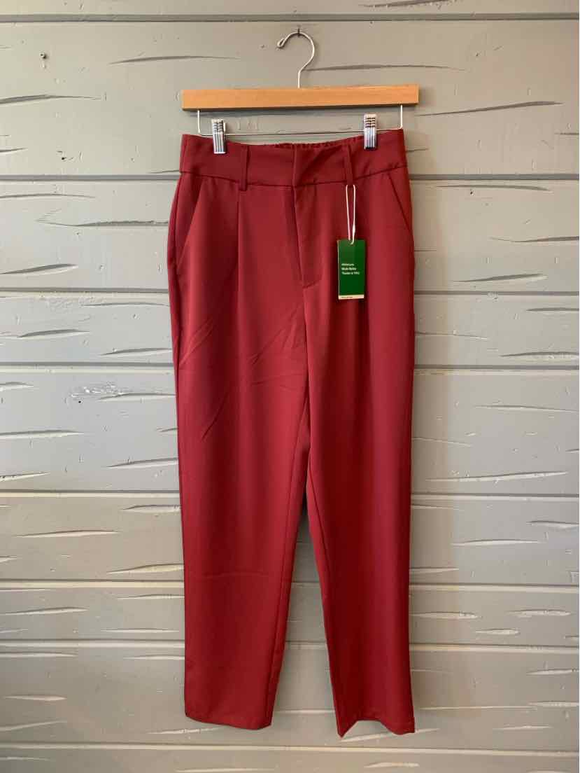 Solid red straight-leg trousers with a flat front, belt loops, and a green hang tag.