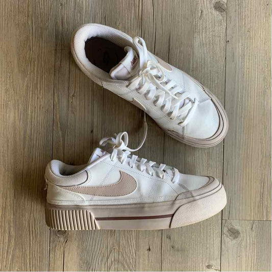White Nike PL sneakers with light beige swoosh, thick textured sole, and lace-up design in women's size 10.