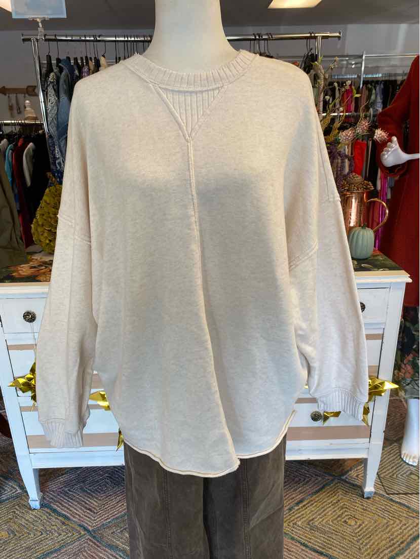 Light beige long-sleeve knit sweater with crew neckline and relaxed fit on mannequin.