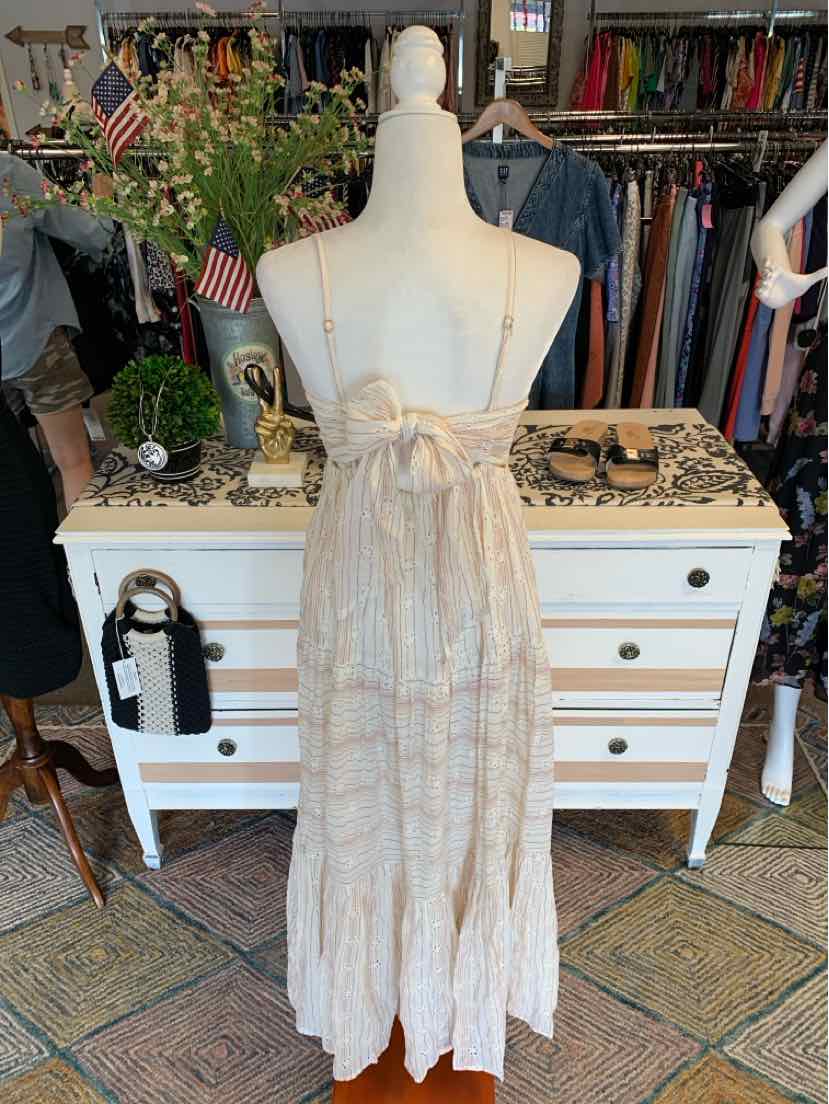 Beige sleeveless maxi dress with eyelet lace details and adjustable tie straps on a white mannequin.