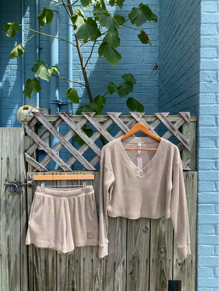 Beige long-sleeve cropped cardigan with buttons paired with matching high-waist shorts.