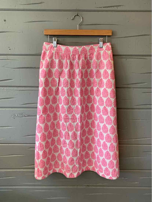 Pink midi skirt with white leaf-like pattern, straight cut, waistband, and side pockets.