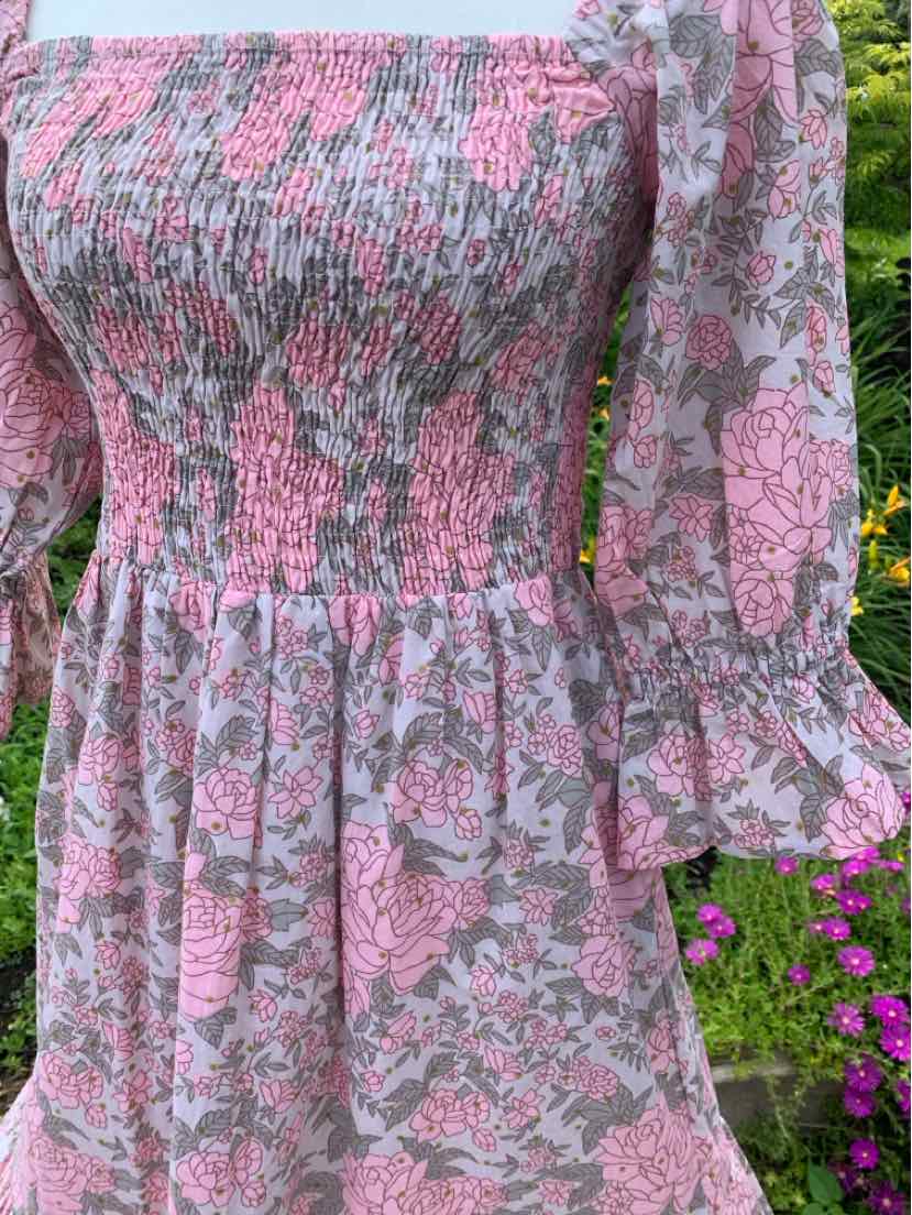 Pink floral long-sleeve dress with gathered bodice and flared sleeves in lightweight fabric.