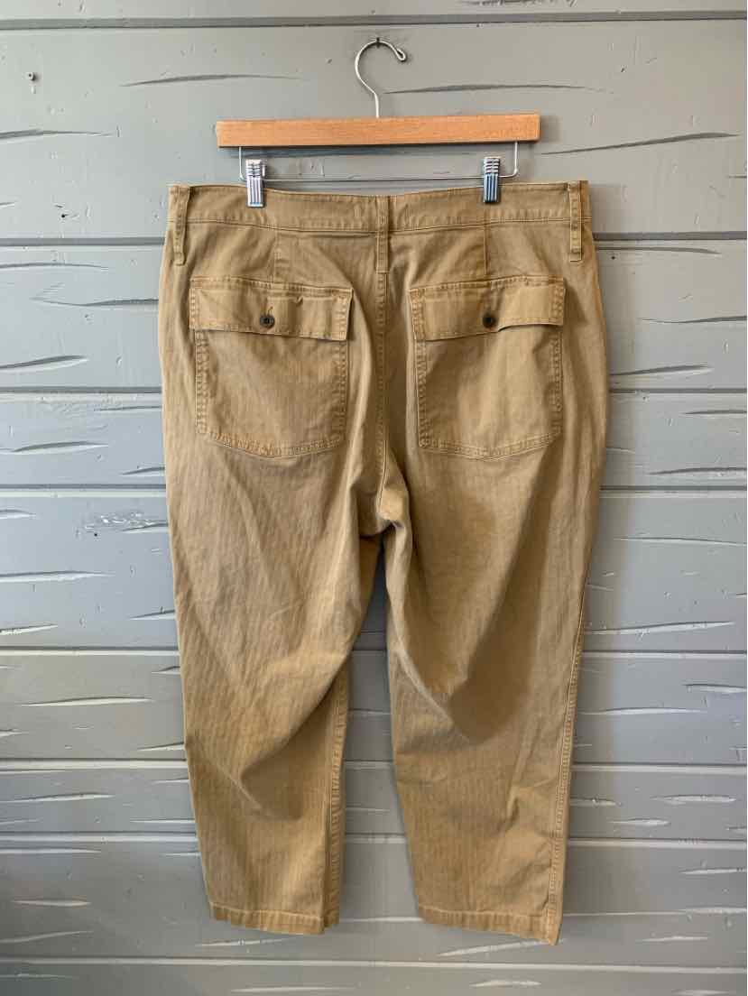 Tan cotton pants size 16 with back flap pockets and button closures hanging on wooden hanger.