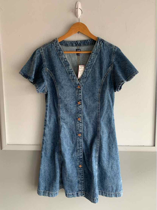 Short-sleeve medium blue denim dress with V-neck and front button closure on wooden hanger.
