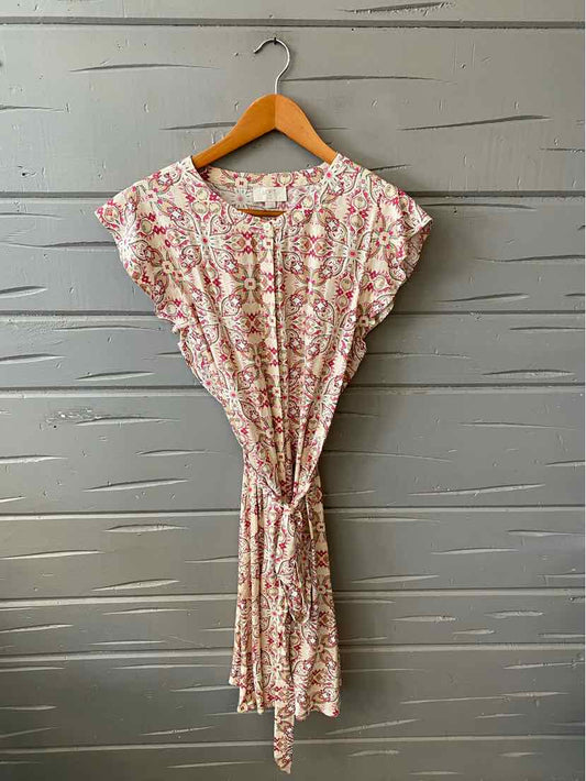 Light pink paisley print dress with ruffled short sleeves and tie waist on wooden hanger.