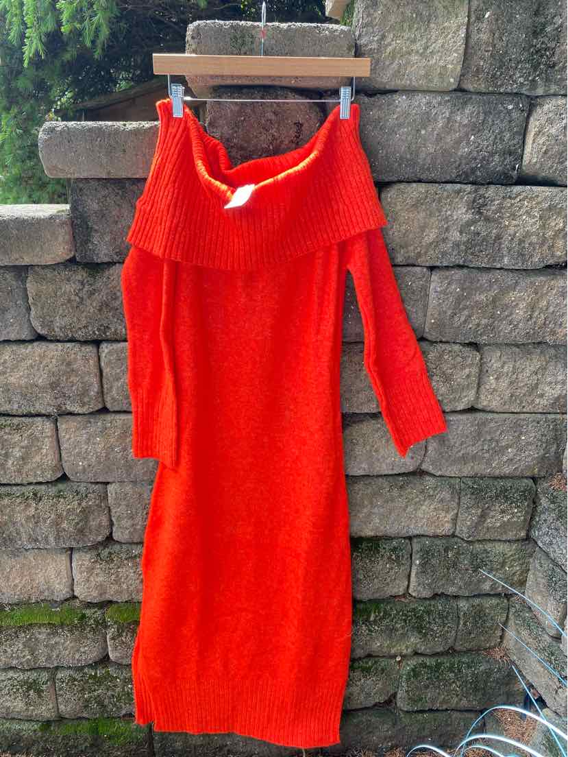 Bright orange off-shoulder knit dress with long sleeves and ribbed collar hanging on wooden hanger.