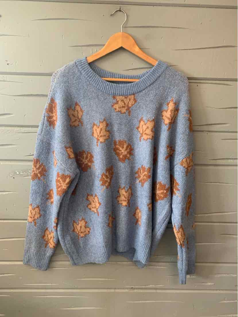 Light blue knit sweater with long sleeves, round neckline, and orange leaf patterns scattered across.