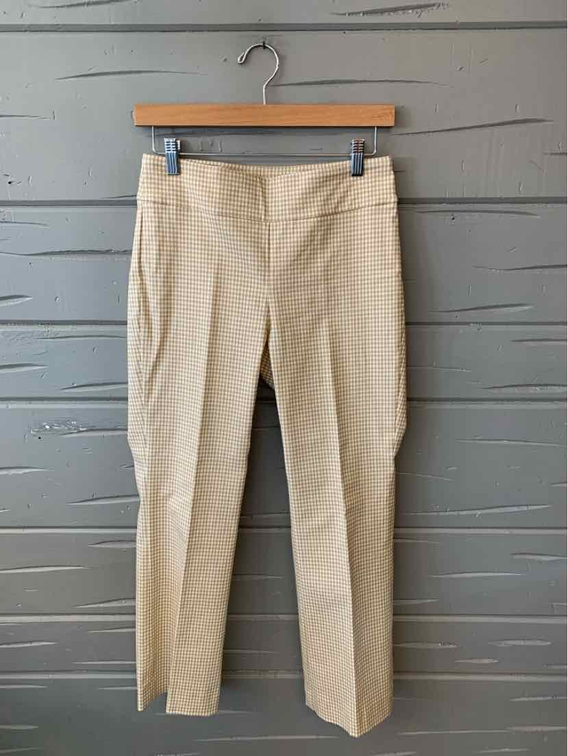 Beige tailored pants with subtle plaid pattern and front seam details hanging on wooden hanger.