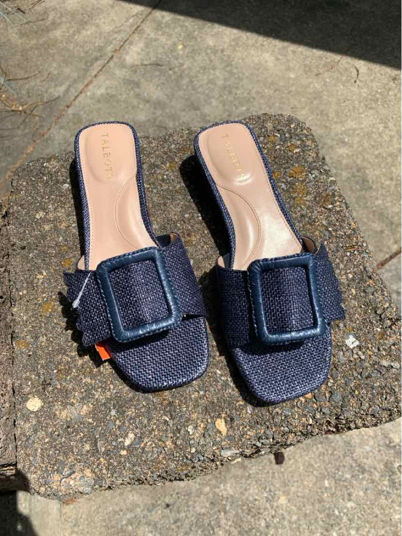 Navy blue slide sandals with square toes and large fabric buckle detail on textured upper.
