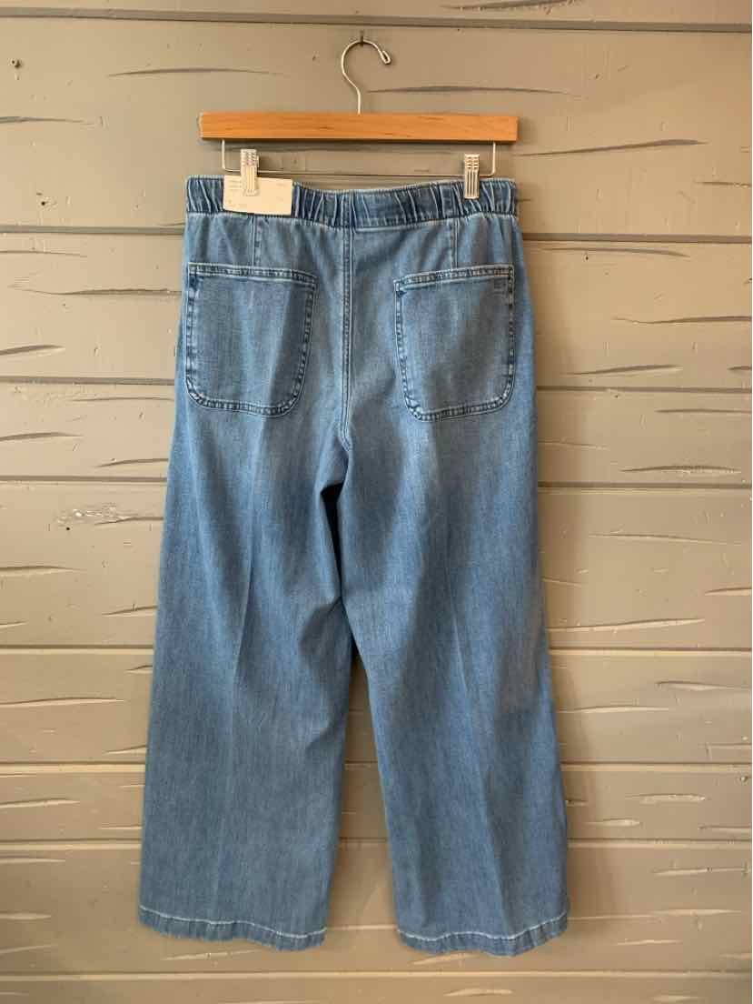 Light blue denim wide-leg jeans with an elastic waistband and two back pockets hanging on a wooden hanger.