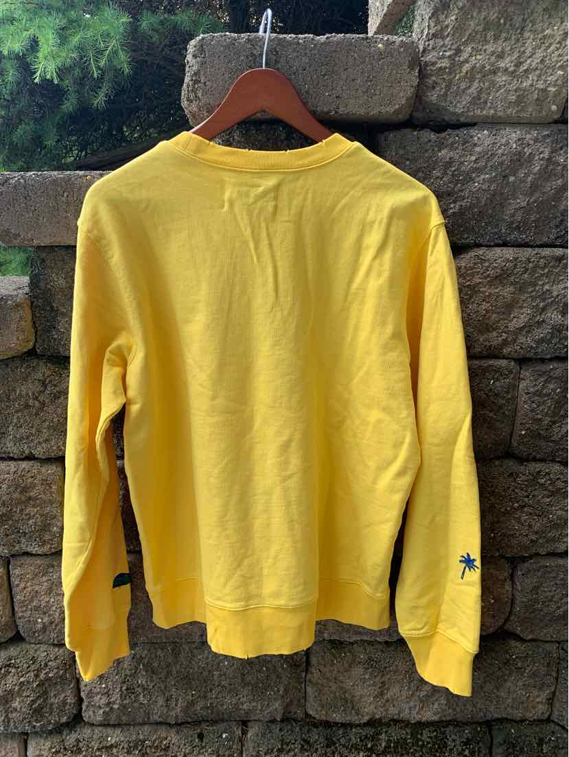 Yellow long-sleeve sweatshirt with ribbed cuffs and waistband, crew neck, and small blue logo on sleeve cuff.