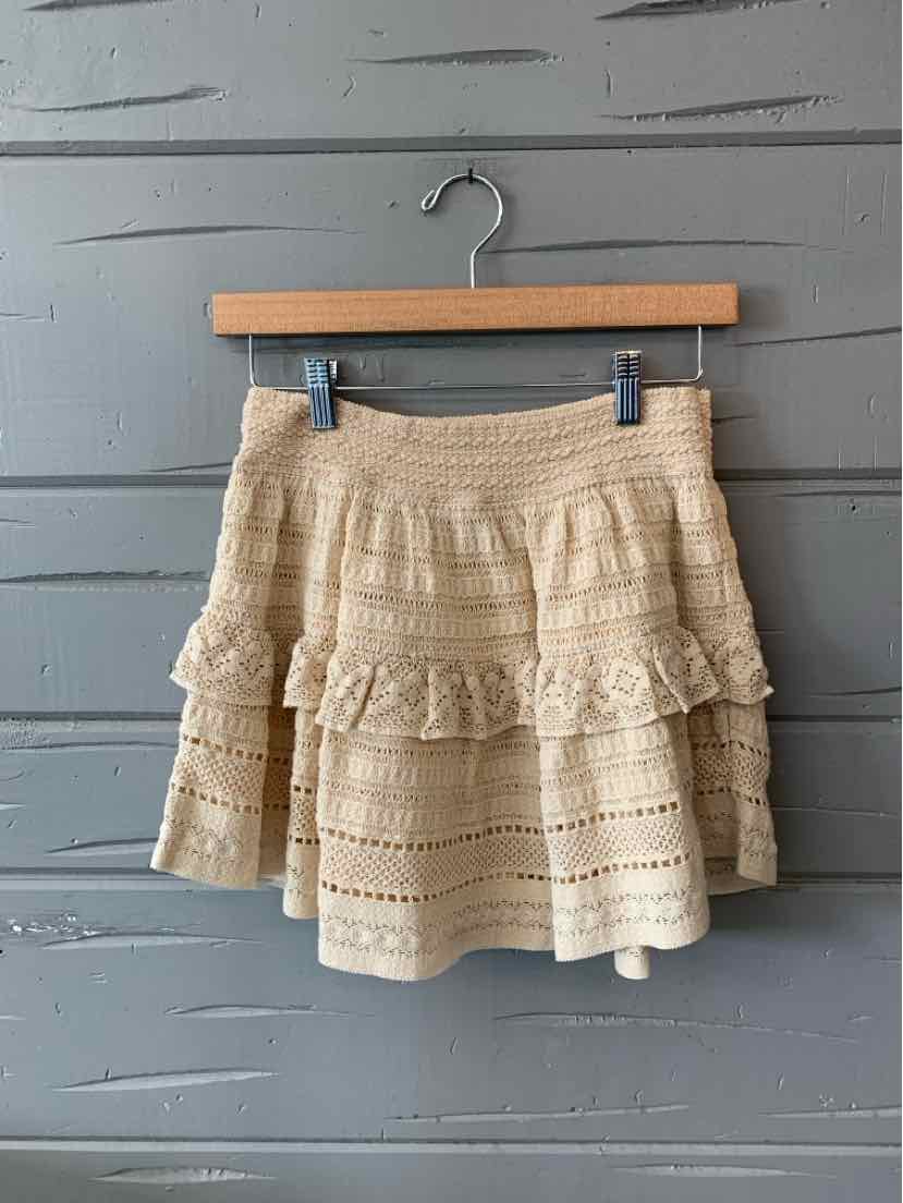 Cream-colored lace mini skirt with layered ruffles and an elastic waistband.