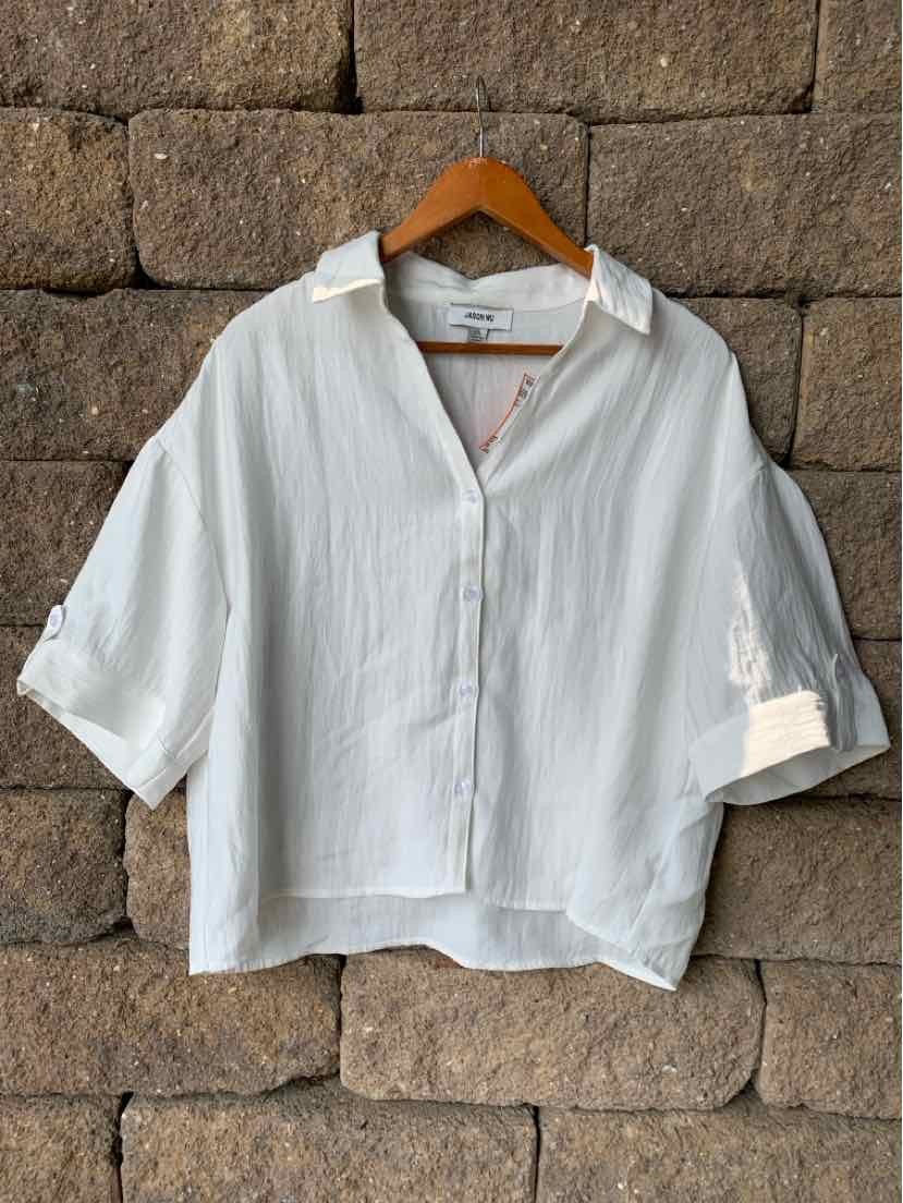 White oversized button-up shirt with 3/4 sleeves and a relaxed collar on wooden hanger.