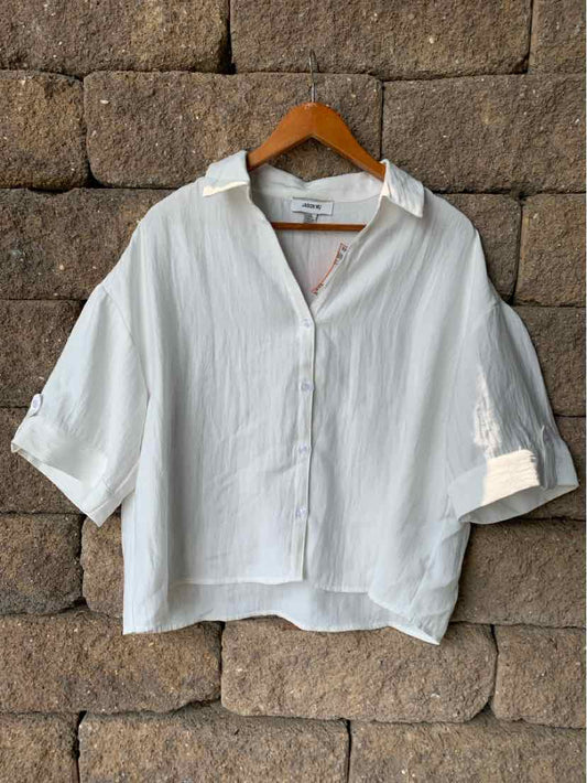 White oversized button-up shirt with 3/4 sleeves and a relaxed collar on wooden hanger.