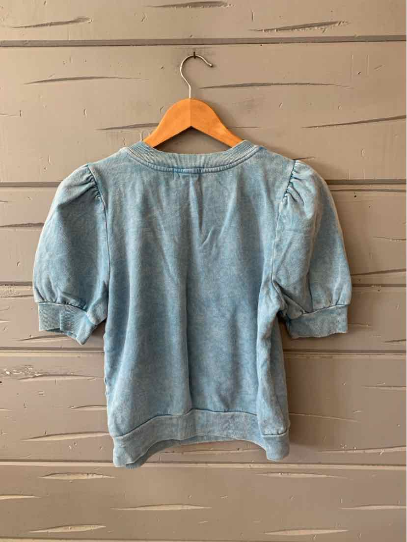 Light blue short-sleeve sweatshirt with puffed shoulders and ribbed cuffs hanging on wooden hanger.