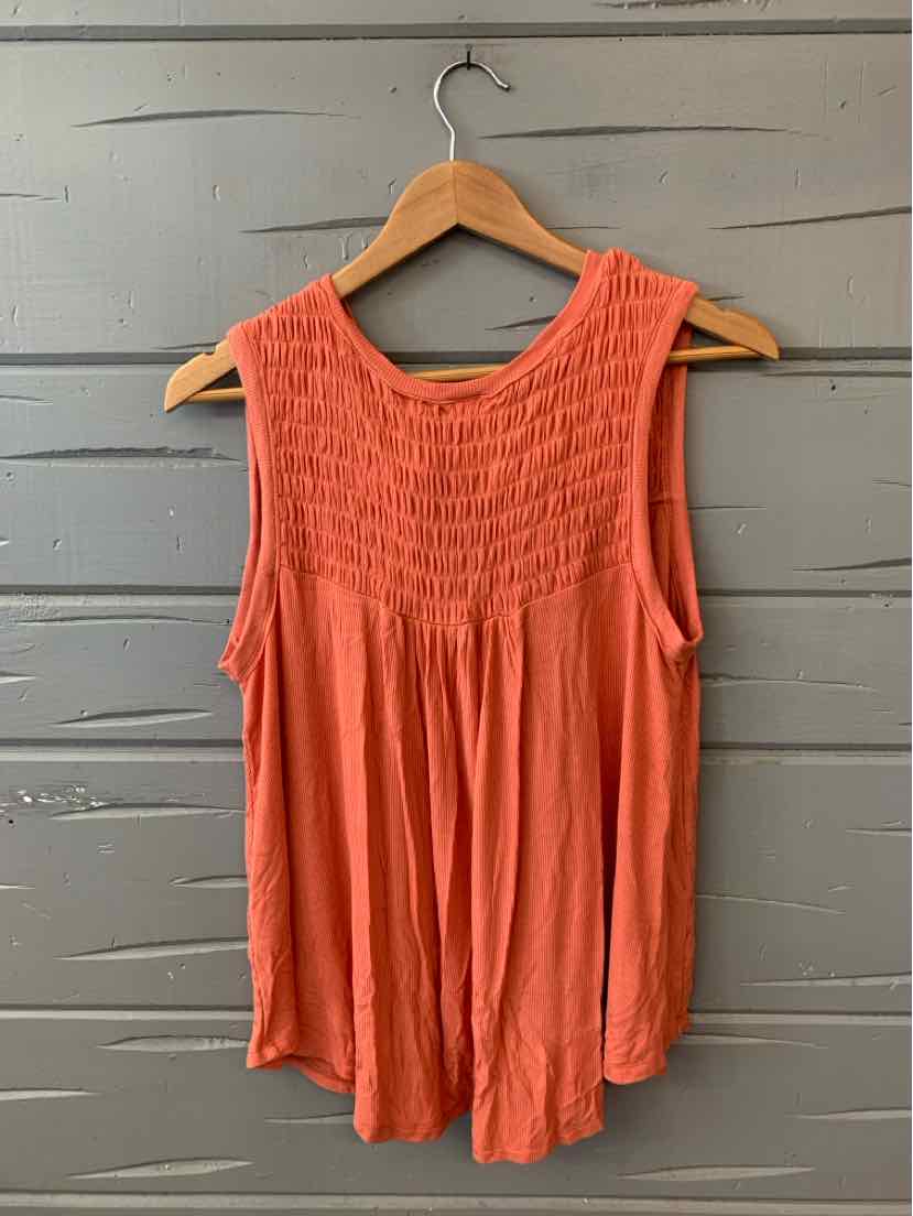 Orange sleeveless top with smocked yoke and flowing fabric hanging on wooden hanger against gray wall.