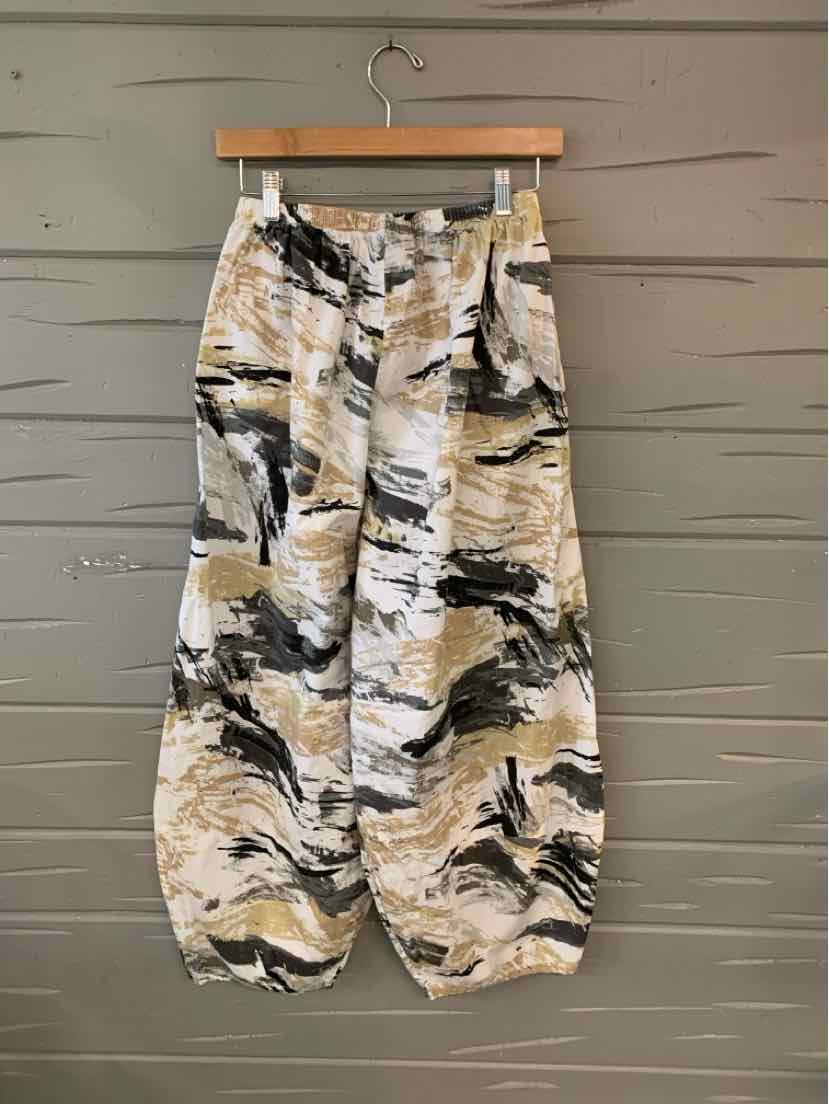 Multi-color patterned wide-leg pants with elasticized cuffs and high waist hanging on wooden hanger.