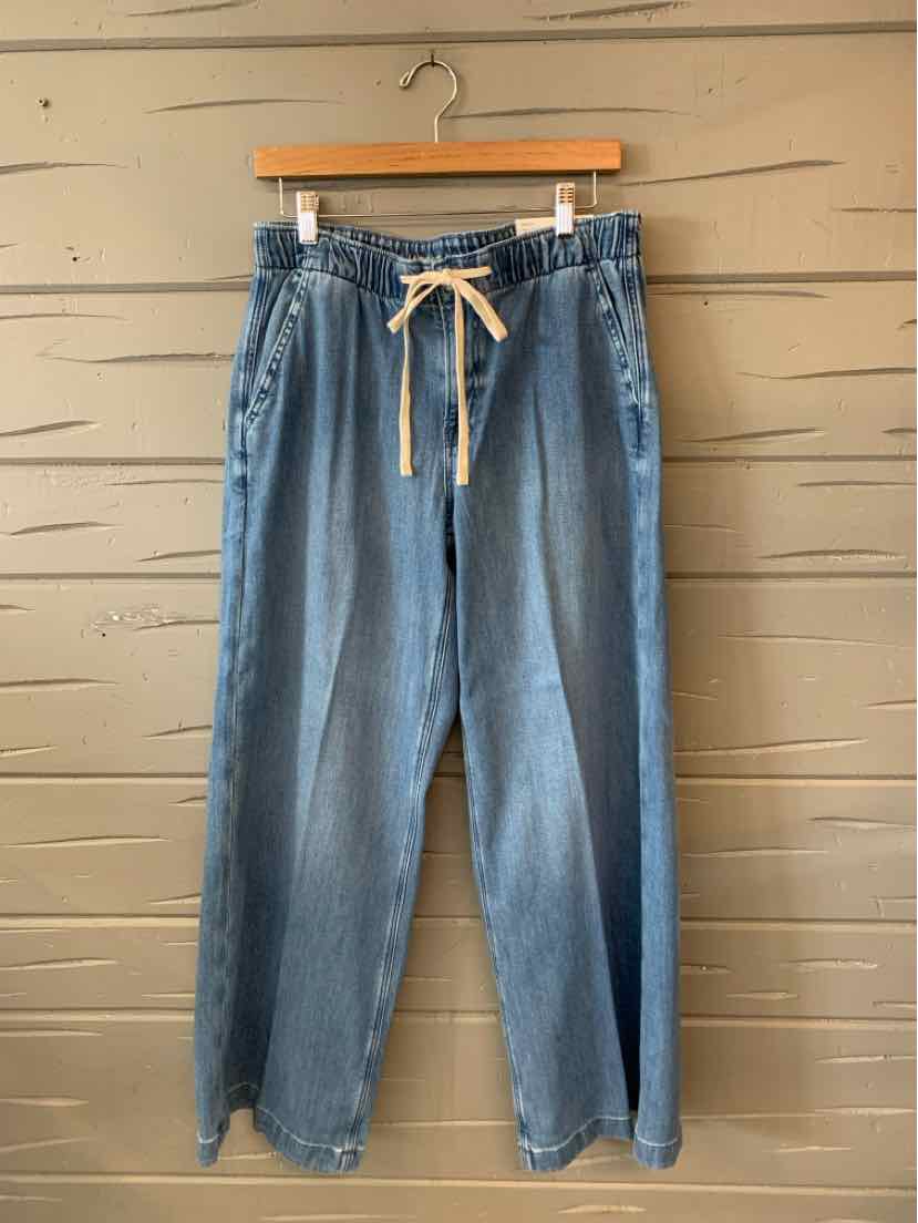 Light blue denim jeans with a white drawstring waistband and relaxed straight legs hanging on a wooden hanger.