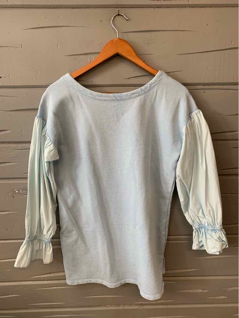 Light blue long-sleeve blouse with gathered puff sleeves and ruffle cuffs on wooden hanger.