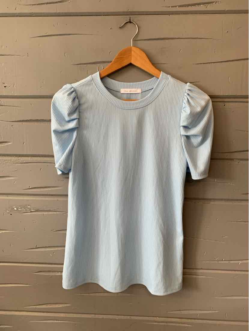 Light blue short-sleeve top with puffed sleeves and round neckline hanging on wooden hanger.