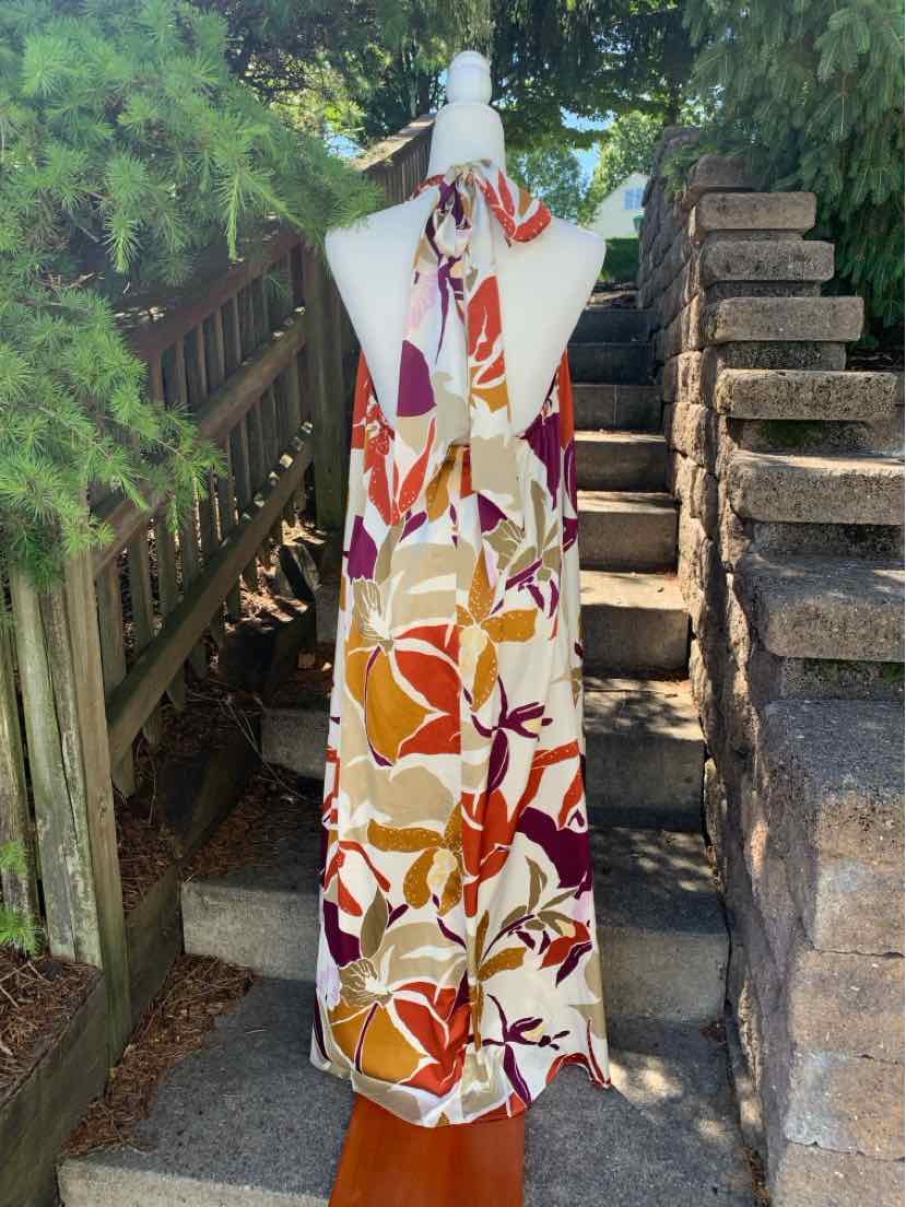 Sleeveless maxi dress with fall-toned floral print in orange, brown, yellow, and white.
