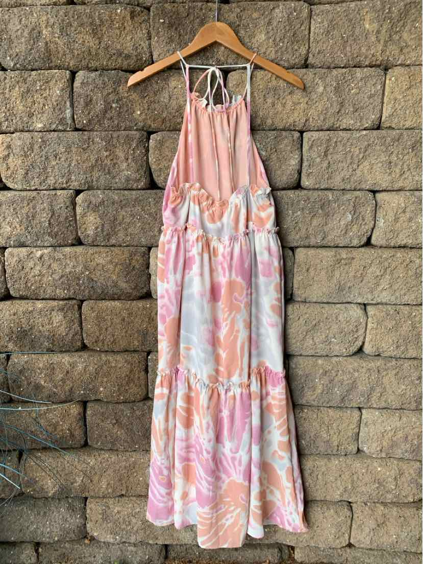 Pink and white watercolor floral halter maxi dress with tiered skirt on wooden hanger.