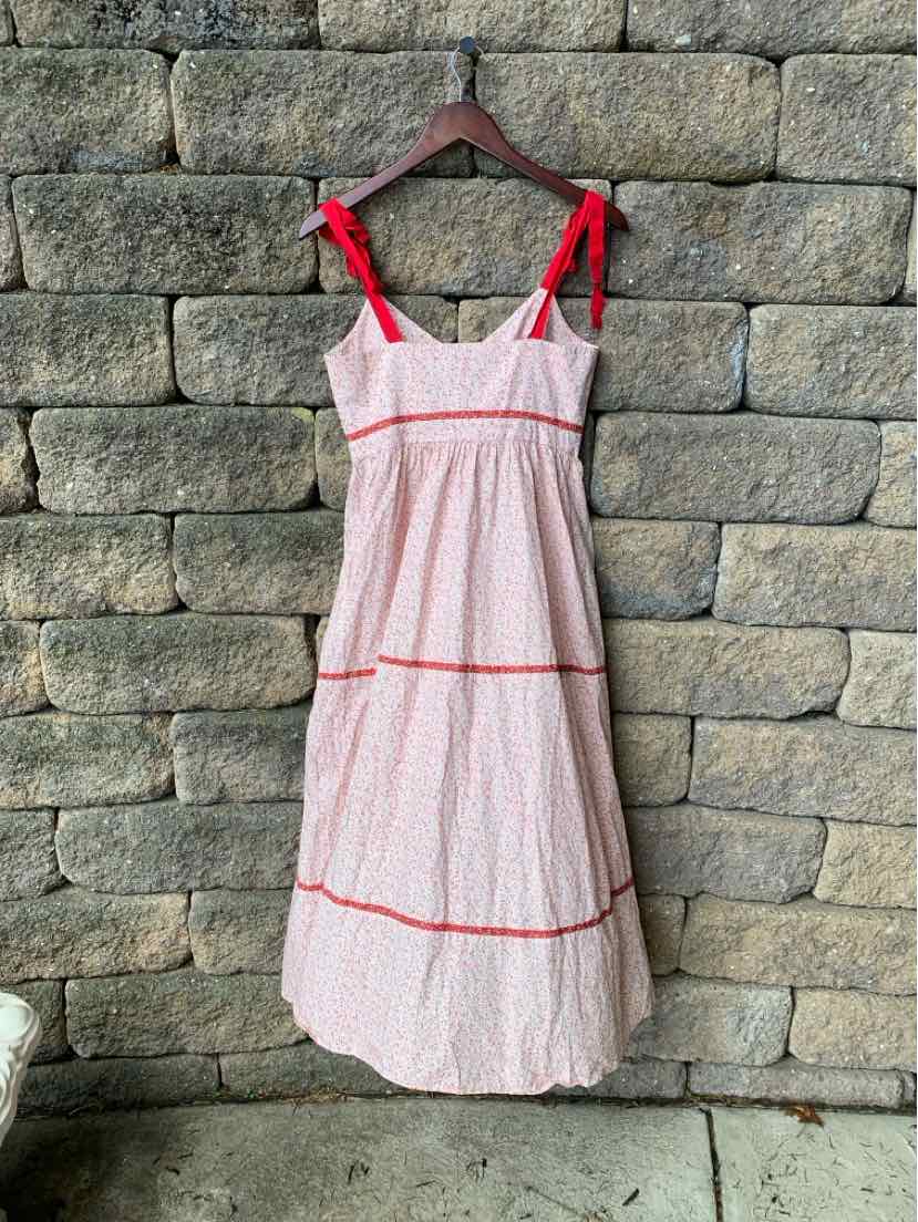 Light pink floral sundress with red tie shoulder straps and red trim details, tiered skirt.