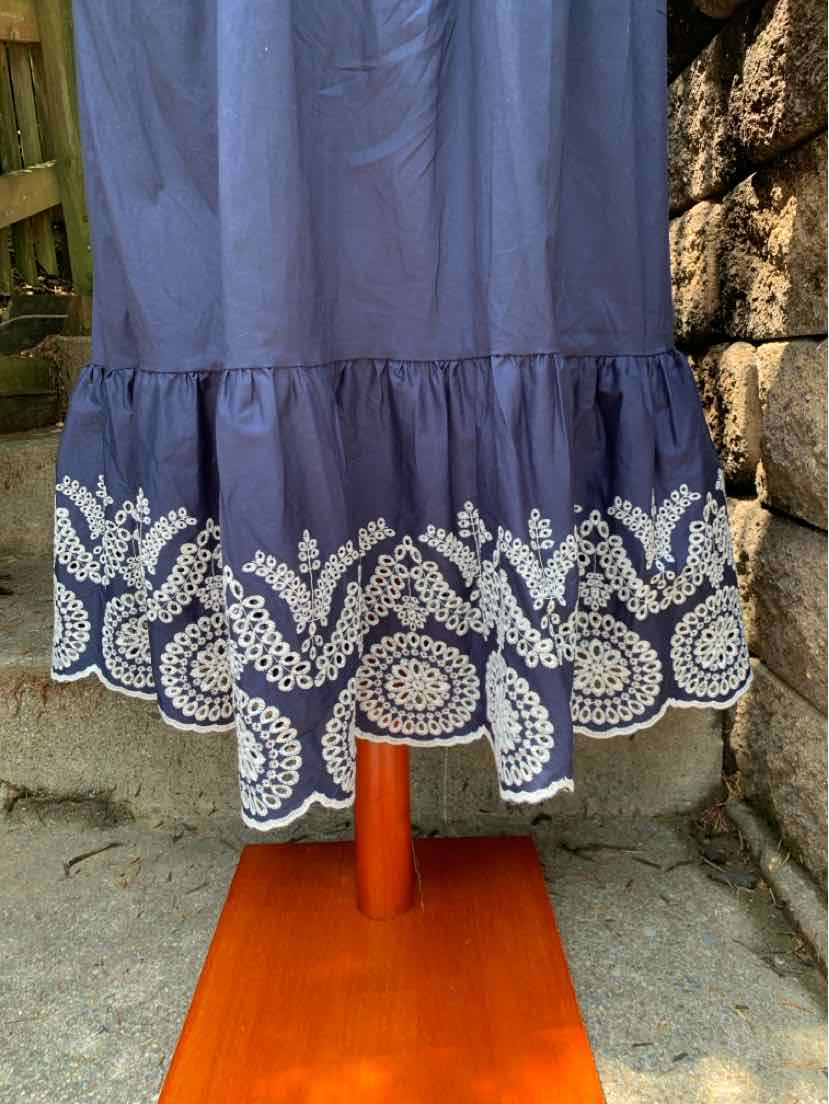 Navy blue dress with white eyelet lace trim and ruffled hem, knee-length style.