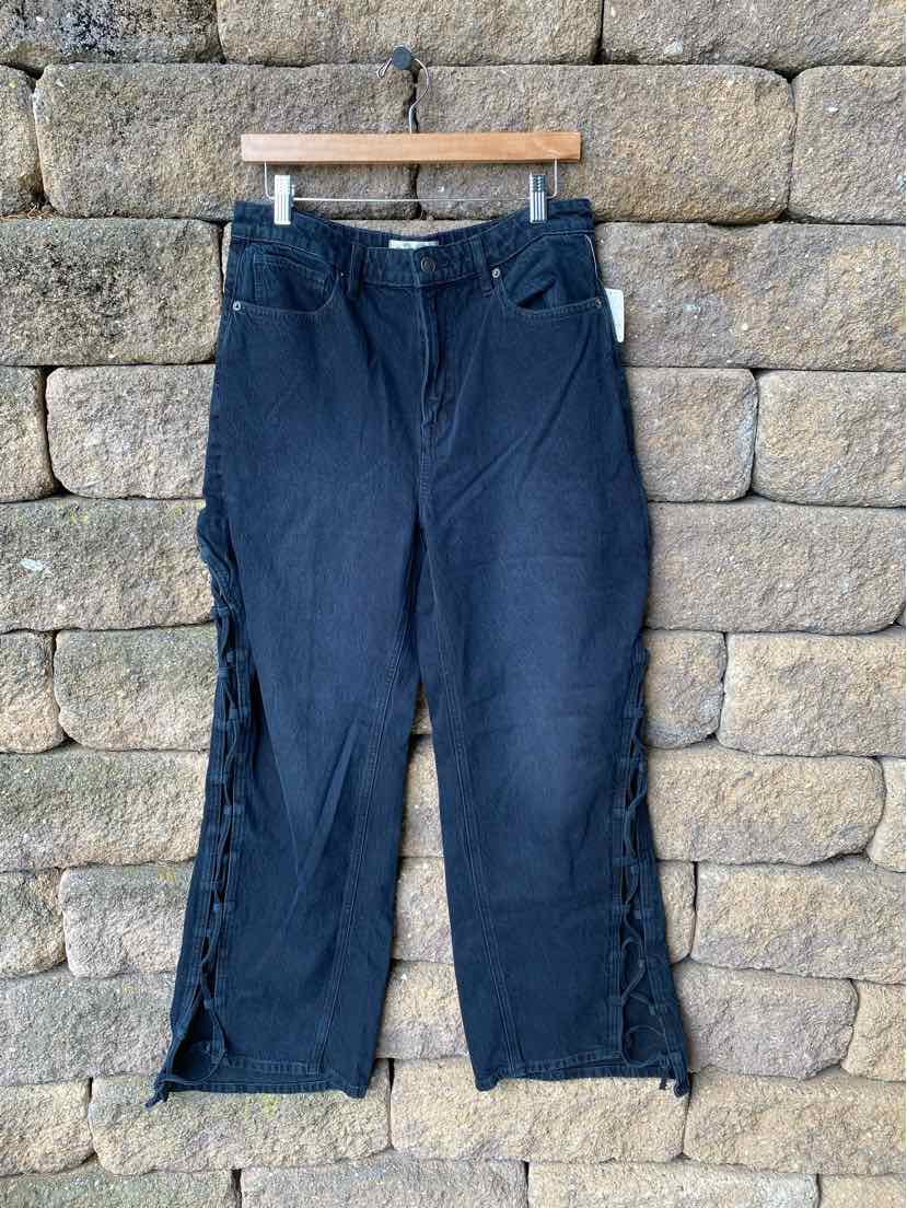 Black denim wide-leg pants with frayed hems and front pockets, size 10, hanging on wooden hanger.