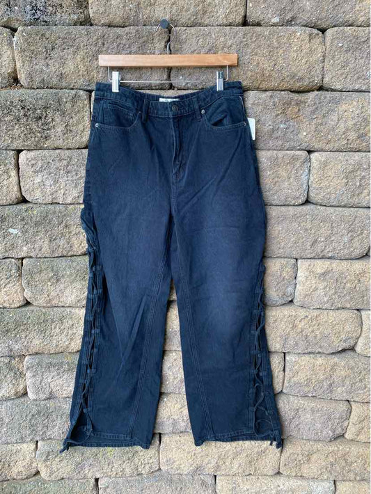 Black denim wide-leg pants with frayed hems and front pockets, size 10, hanging on wooden hanger.