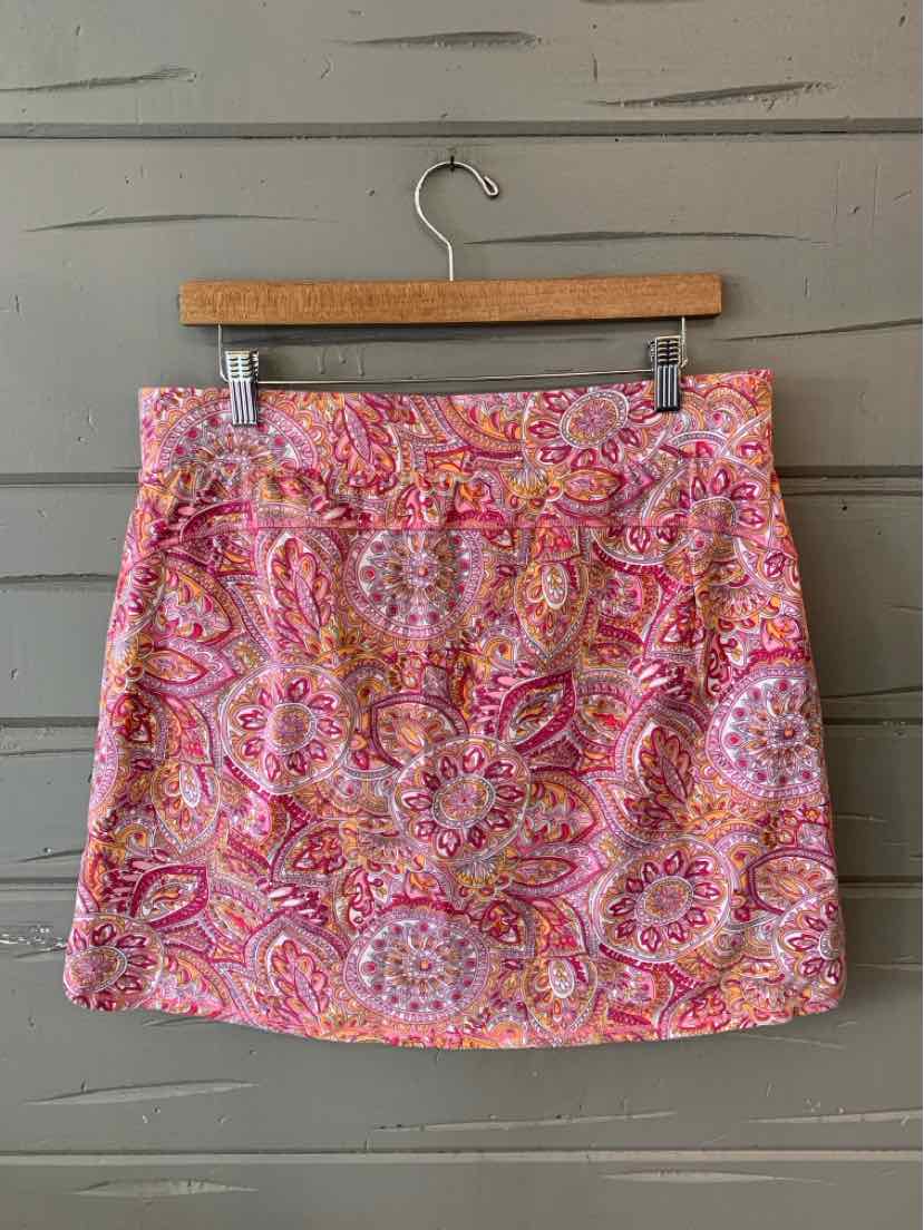 Pink paisley print skirt with front pockets and straight hem hanging on wooden hanger.