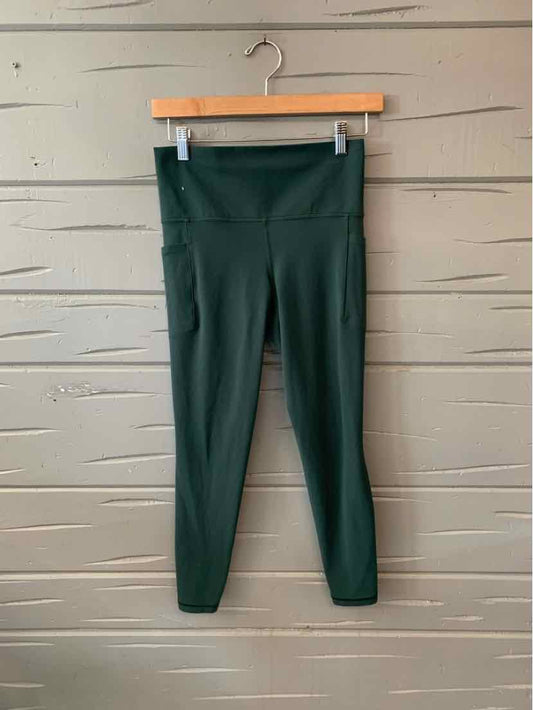 High-waist dark green leggings with smooth, solid fabric and a slim fit hanging on a wooden hanger.