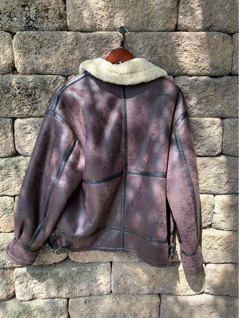 Brown shearling jacket with cream fur collar and seam detailing, cropped fit, and long sleeves.