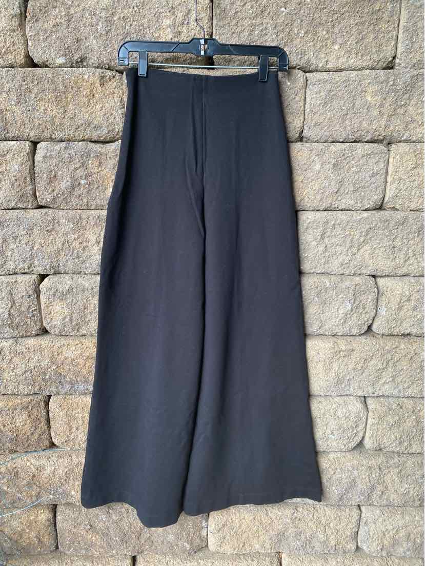 Black wide-leg pants in medium size with a smooth, solid fabric hanging on a hanger.