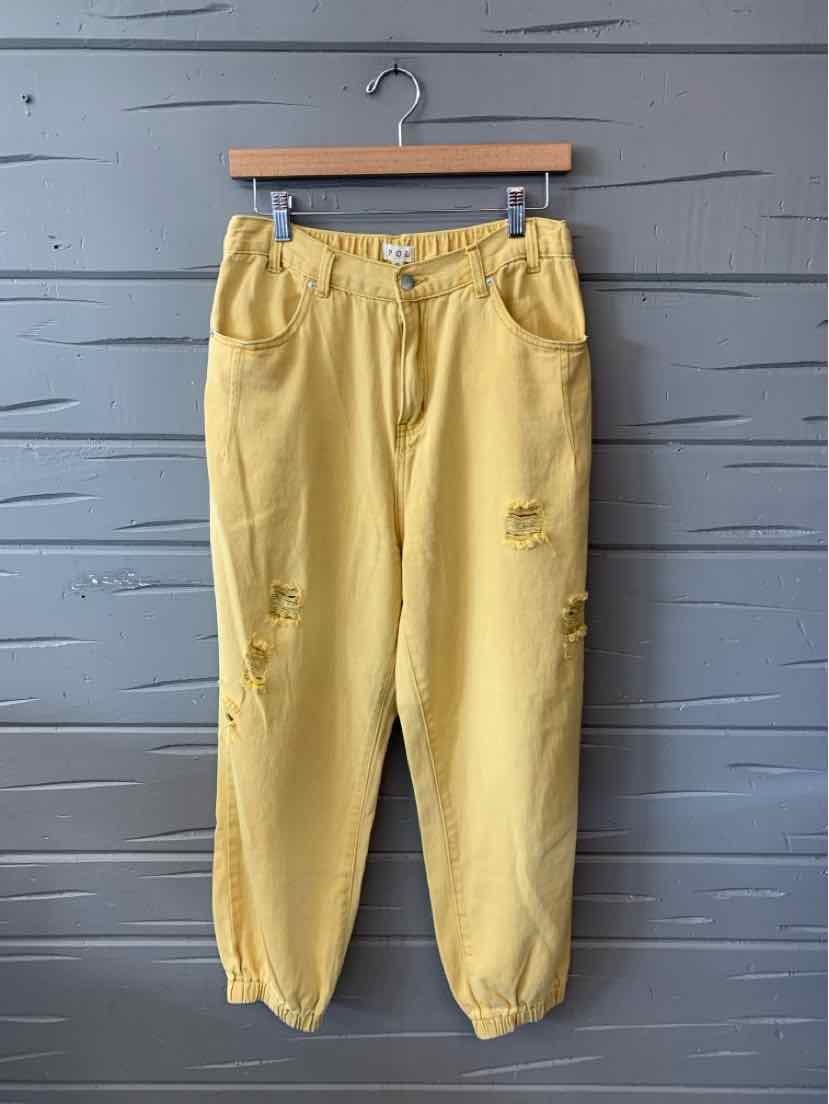 Yellow high-waist relaxed-fit pants with front button and zipper, elastic cuffs, and distressed details.