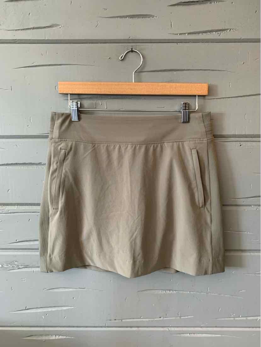 Beige solid casual skirt with front pockets and a wide waistband hanging on wooden hanger.